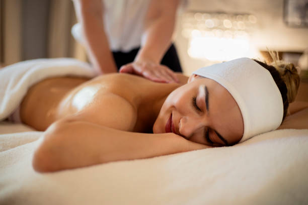 Happy woman havng back massage. Shallow DOF. Developed from RAW; retouched with special care and attention; Small amount of grain added for best final impression. 16 bit Adobe RGB color profile.